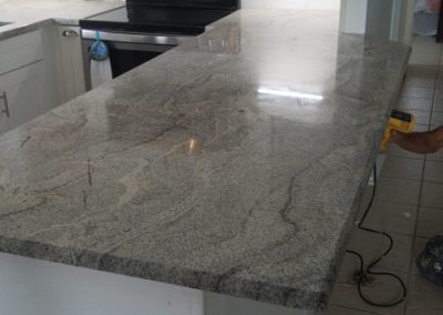 kitchen counter top done with white and grey granite and a big peninsula
